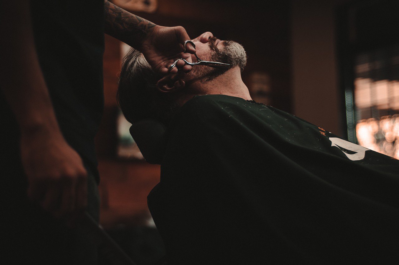 Barbero recortando barba a cliente